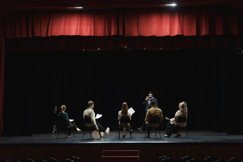theater actors practicing their script while seated at the stage