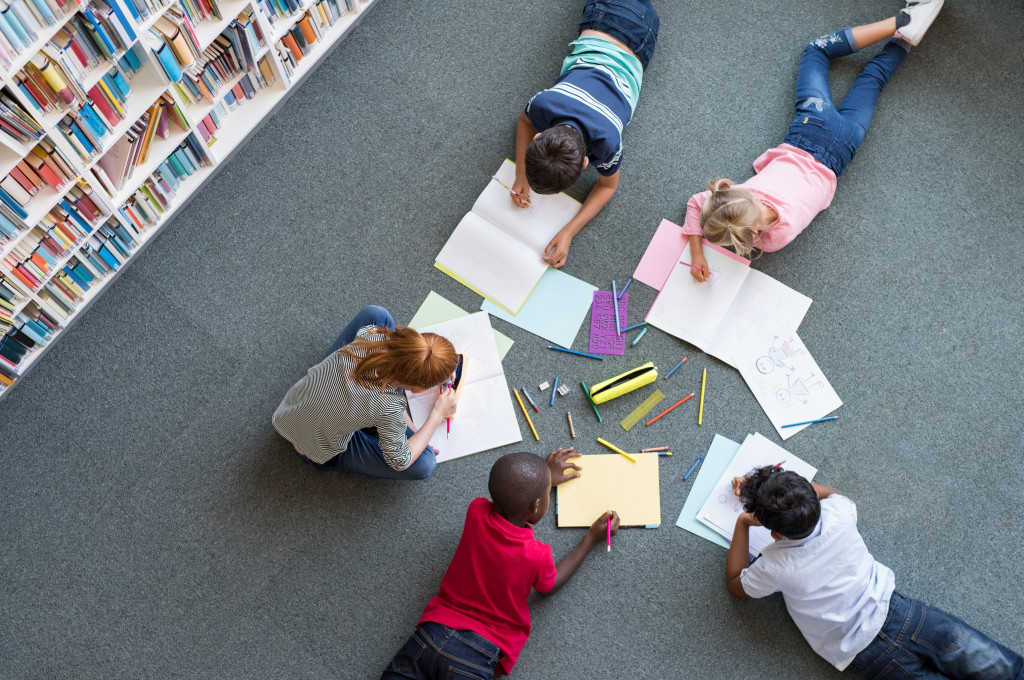 Top view of a group of kids doing an arts project while on a carpeted floor